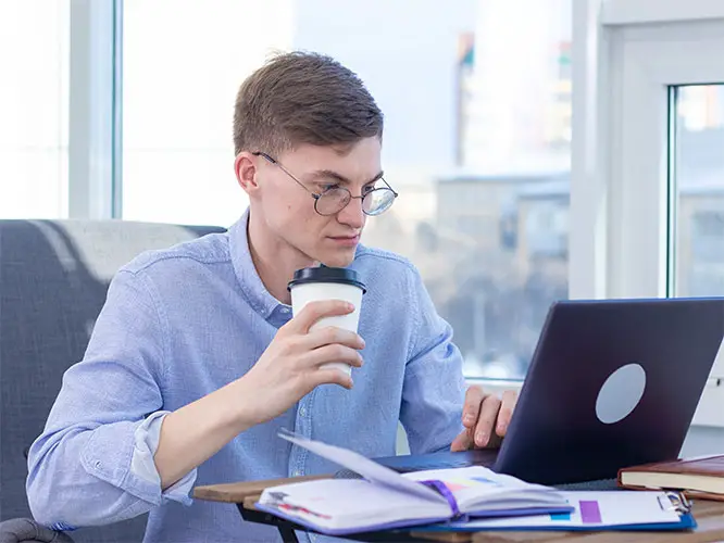 un homme portant des lunettes devant un ordinateur portable